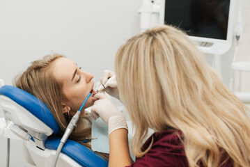 The dentist begins a routine operation to clean the tartar of the female mouth.