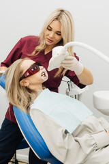 The doctor performs a professional teeth whitening procedure with an ultraviolet lamp.