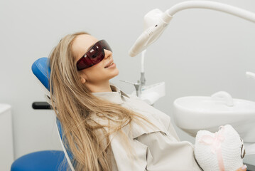 Teeth whitening procedure with ultraviolet light UV lamp. Close-up portrait of a female patient at...