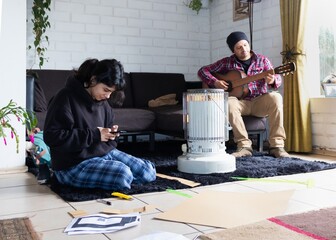 Dad playing the guitar while his daughter does her homework
