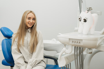 Fototapeta premium Satisfied dentist patient showing her perfect smile after treatment in a clinic box with medical equipment in the background