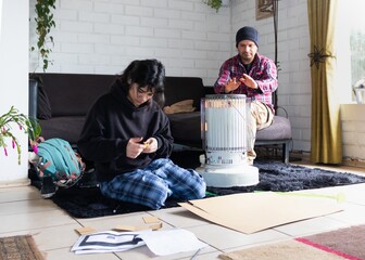 father and daughter next to the kerosene stove in their home