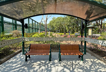Wooden garden bench with outdoor exerise equipment green plants and tree
