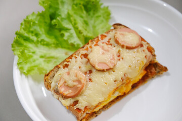 Homemade pizza made from white bread with sausage and cheese toppings