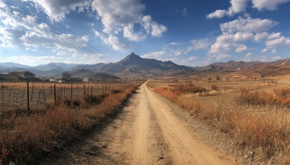 Fototapeta premium Dirt road winds through a dry landscape towards a mountain