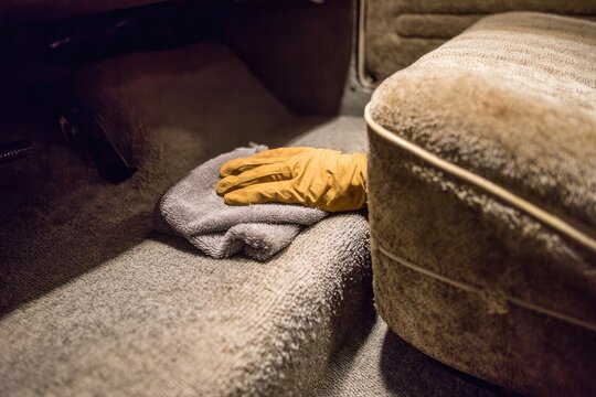 Fototapeta A gloved hand cleans car interior carpet
