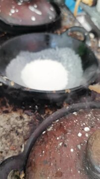 A vendor at a traditional market prepares serabi solo (solo pancakes) using a clay mold on a stove.
