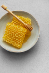 Honeycomb and honey dipper resting in ceramic bowl on table