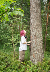 Young biologist touching and studying a tree in the forest