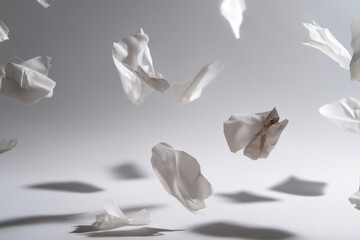 confetti-like white paper fragments drifting gently in the air, scattered randomly with natural folds and shadows, peaceful airy look on white background