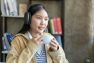 A woman wearing headphones and holding a white cup