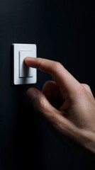 Conceptual image of a a hand turning off a light switch, symbolizing energy conservation. Responsibility, saving. Dark, contrasting.