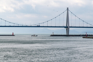 fishing boat and suspension bridge on the cloudy sea