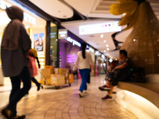 Blurred motion of people shopping inside modern shopping mall interior.