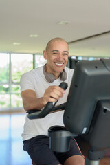 Latin man cycling on stationary exercise bike in gym, training, wellness and healthy lifestyle