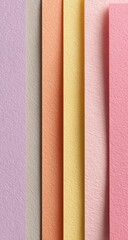 Close-up of several sheets of textured paper in various pastel colors stacked vertically