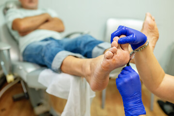 concept of male pedicure, cosmetologist makes classic pedicure for an elderly male client.