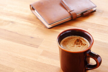 Brown schedule planner, diary, notebook with cup of Coffee on table
