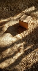 Beige cardboard box on textured rug, sunlight shadows