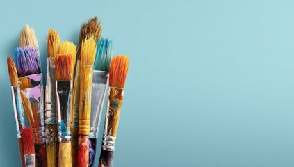 Fototapeta premium Colorful paintbrushes clustered together on a light blue background