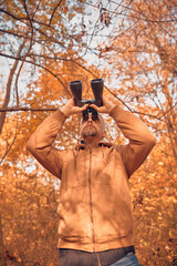 Amateur birdwatcher observing birds and other animals in nature with binoculars.