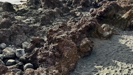 A closeup highlights intricate rocky textures and diverse stones on the beach, showcasing the coastal landscape