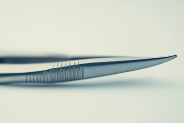 Close up of fine point surgical tweezers against a light background