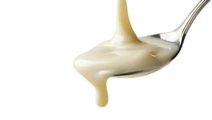 A close-up shot of a spoon with flowing of condensed milk. A trickle of milky goodness is gracefully dripping from the spoon