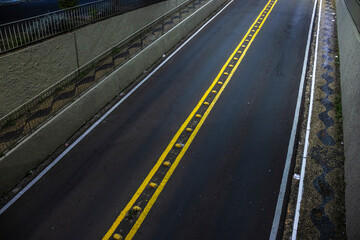 Dark street with yellow lines. Road marking on black asphalt. Urban scene in Brazil