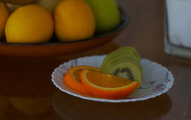 There are sliced kiwis and oranges on the plate.