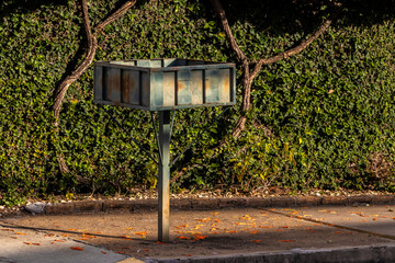 empty support for garbage bags on the sidewalk in front of the green wall of a residence in Brazil