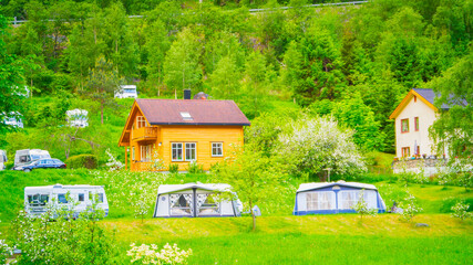 A house and a tent set amid the mountains of Flåm, Norway, represent a concept of sustainable tourism and living in harmony with nature.