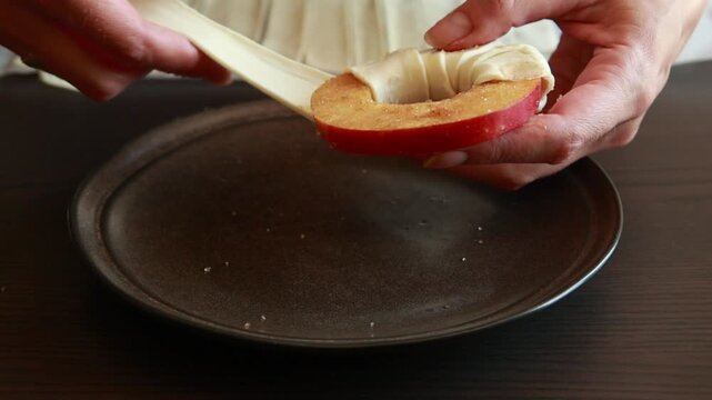close-up video of hands covering a fresh slice of apple with puff pastry dough, perfect for dessert preparation, fall baking, and cooking tutorials