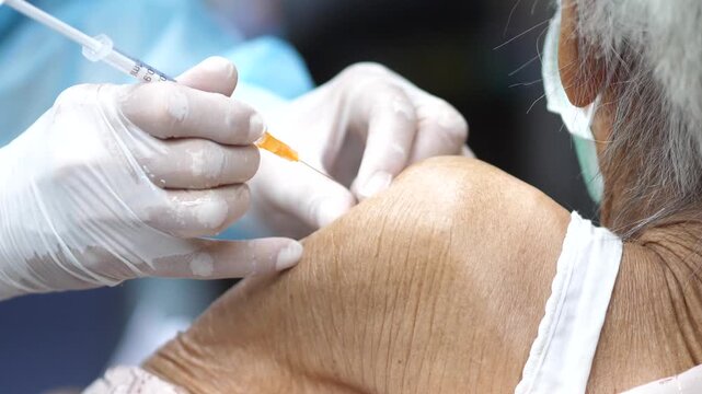 Healthcare worker administering a vaccine injection to a patient&rsquo;s arm, close-up view