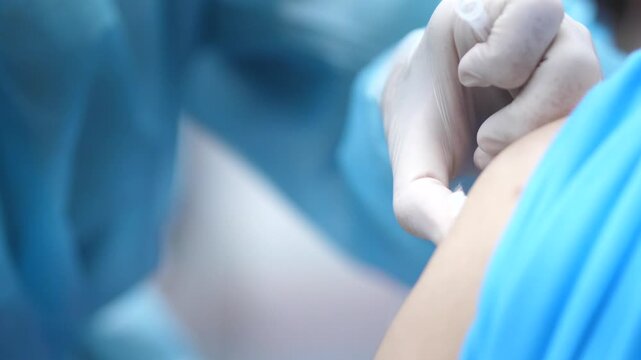 Healthcare worker administering a vaccine injection to a patient&rsquo;s arm, close-up view