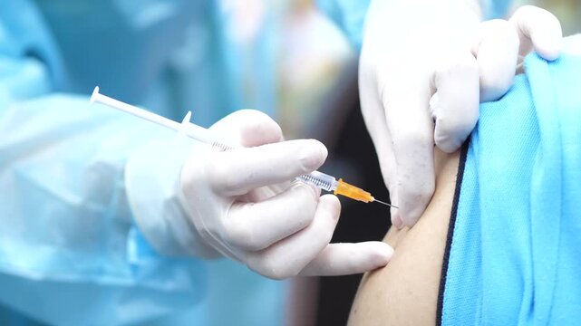 Healthcare worker administering a vaccine injection to a patient&rsquo;s arm, close-up view