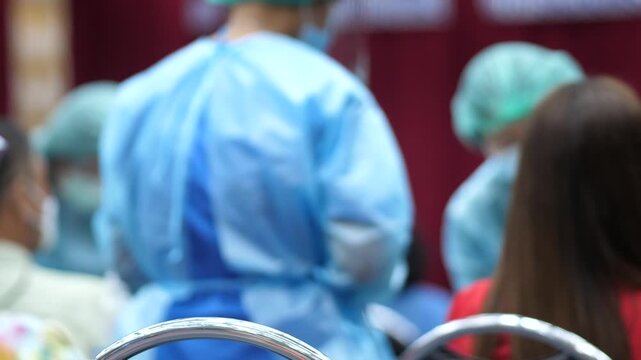 Blurred view of healthcare workers in protective clothing preparing to administer vaccines