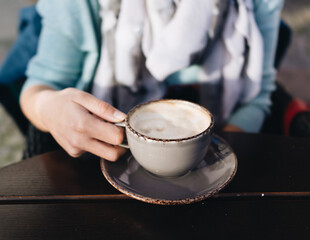 Cozy cafe morning with a woman enjoying a steaming cup of frothy cappuccino in stylish ceramic mug