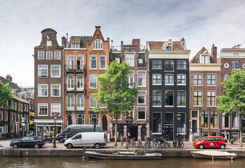 Charming Canal Side Architecture Featuring Iconic Amsterdam Townhouses on a Sunny Day with Vehicles and Trees