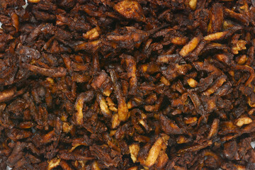 A pile of baked grated smoked tofu in a soy and mustard marinade is on baking paper, photographed from above