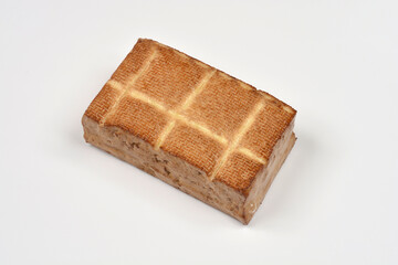 A single block of smoked tofu is placed on a white background, photographed from an angled top-down perspective