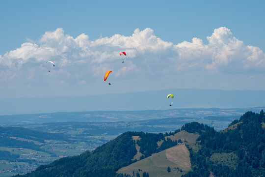 Des personnes qui pratiquent la parapente volent dans le ciel des pr&eacute;alpes suisses