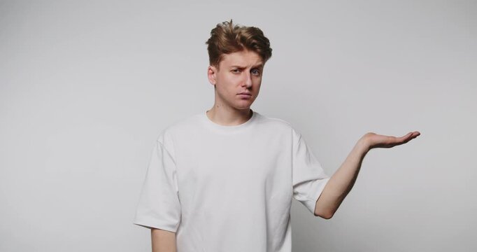 footage of young man shows a disappointed expression while gesturing his hand outwards on beige background