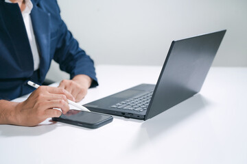 Business man  using a laptop and a cell phone at the same time.