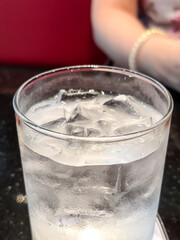 Glass of water with ice cubes on table