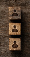 Three wooden blocks, vertically aligned, each imprinted with a person icon.  Dark wood background