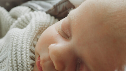 Close-up of newborn baby sleeping peacefully in knitted blanket