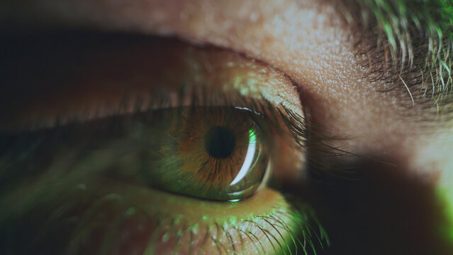 Human eye reflecting green light showing futuristic concept