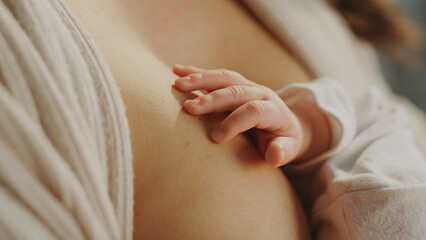 Newborn baby hand touching mother's skin during breastfeeding