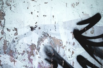 Grungy urban wall texture with black spray paint marks, peeling paint, distressed surface. 90s,...